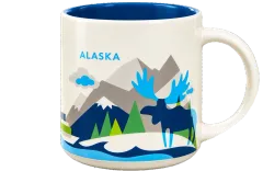The Alaska mug: cream ceramic with a blue inside, illustrated mountains, evergreens and a moose