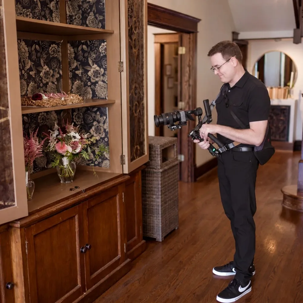 Brian filming the rings and bouquet set out in a wallpapered cabinet at CJ's Off the Square