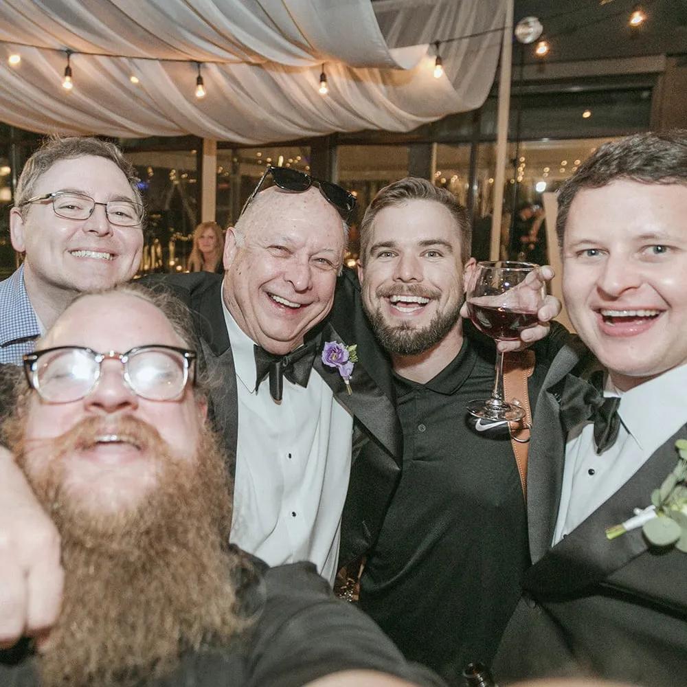 Reception selfie: Brian and Micah with our second-shooter photographer, the groom and the father of the groom, string lights and city views behind them