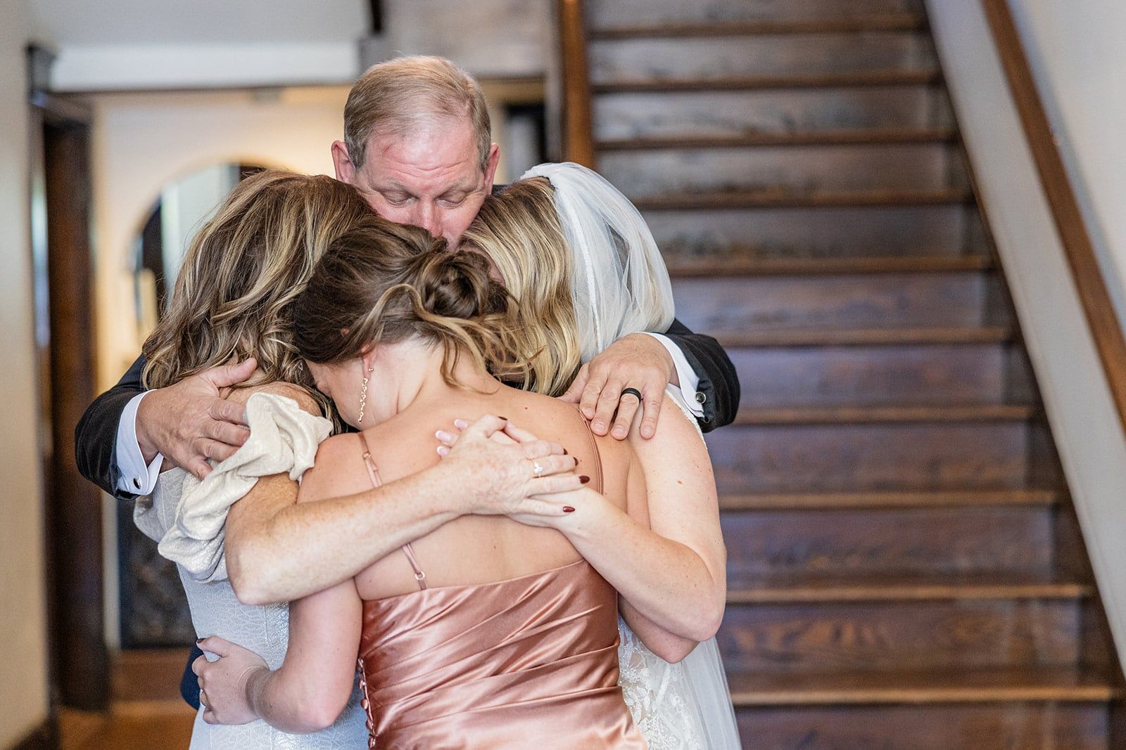 A tearful group hug with Caitlin's dad at the foot of the stairs after their first look