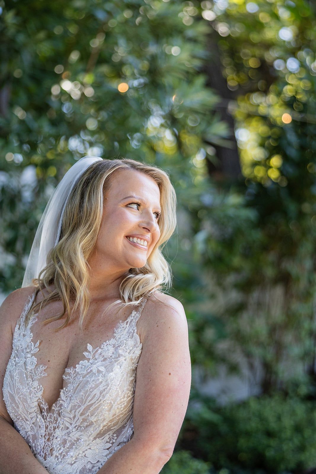 Caitlin glances over her shoulder in the garden, light catching her hair