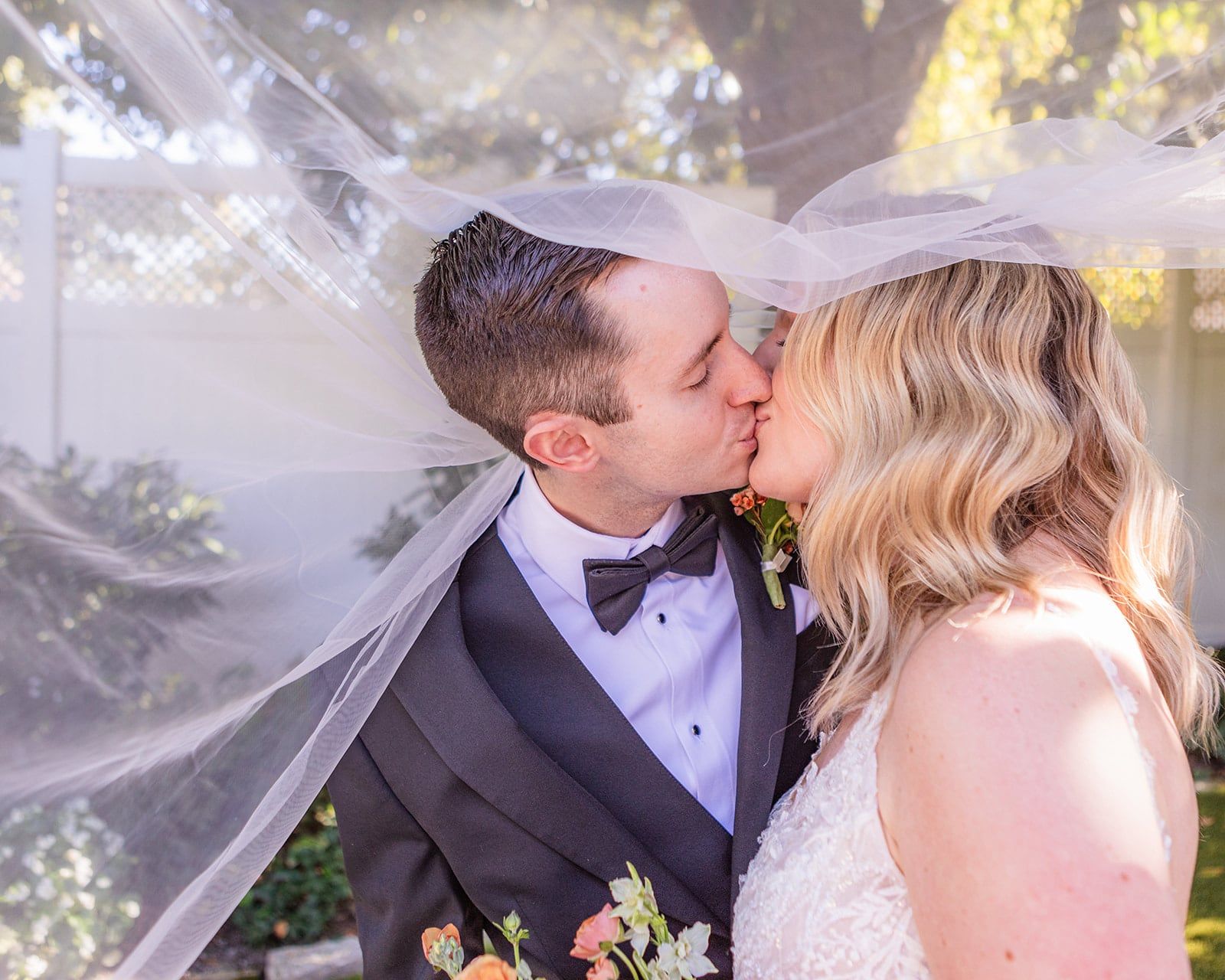 Caitlin and Gunnar kiss under her veil as it lifts in the breeze