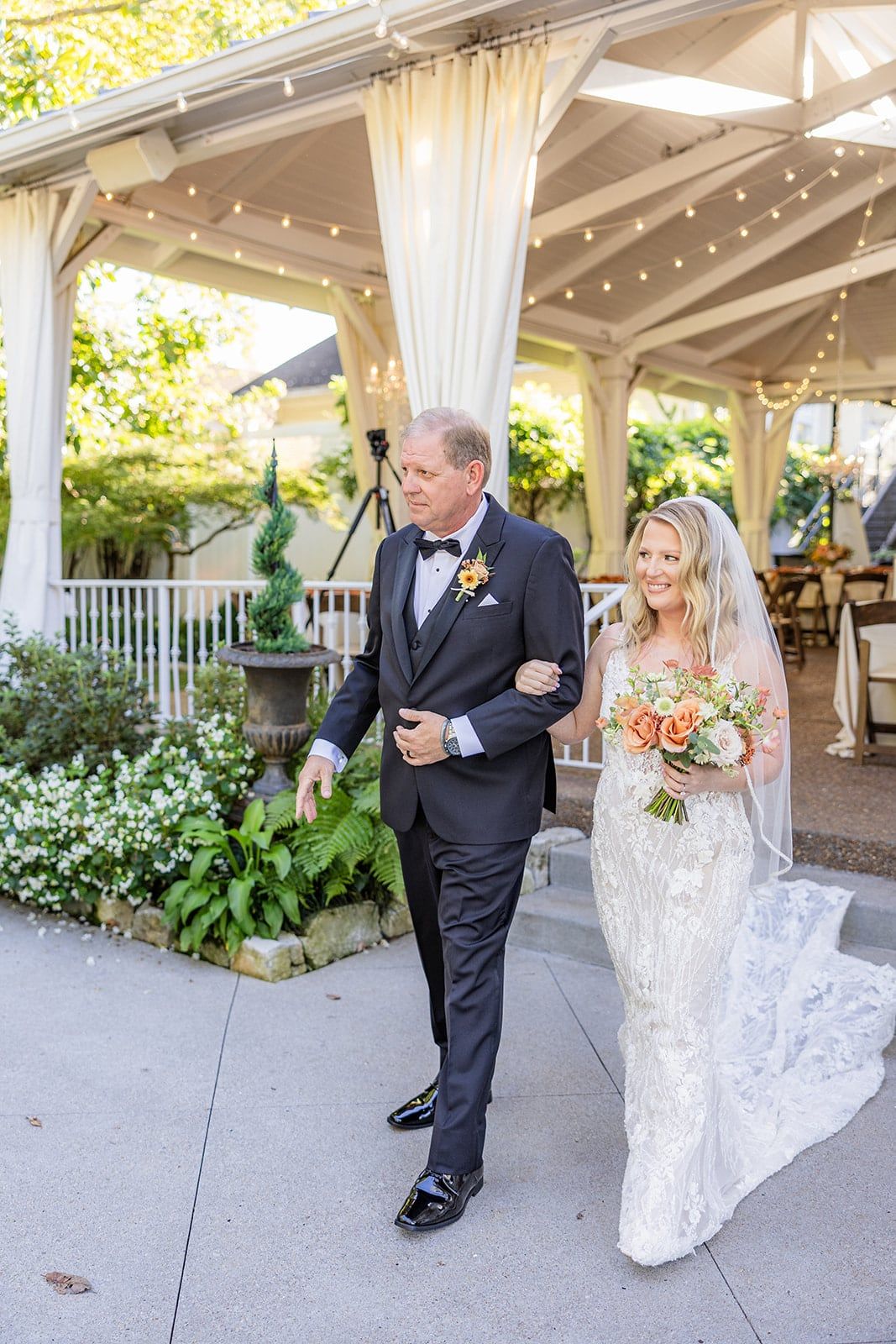 Caitlin's dad walks her toward the ceremony past the garden pavilion