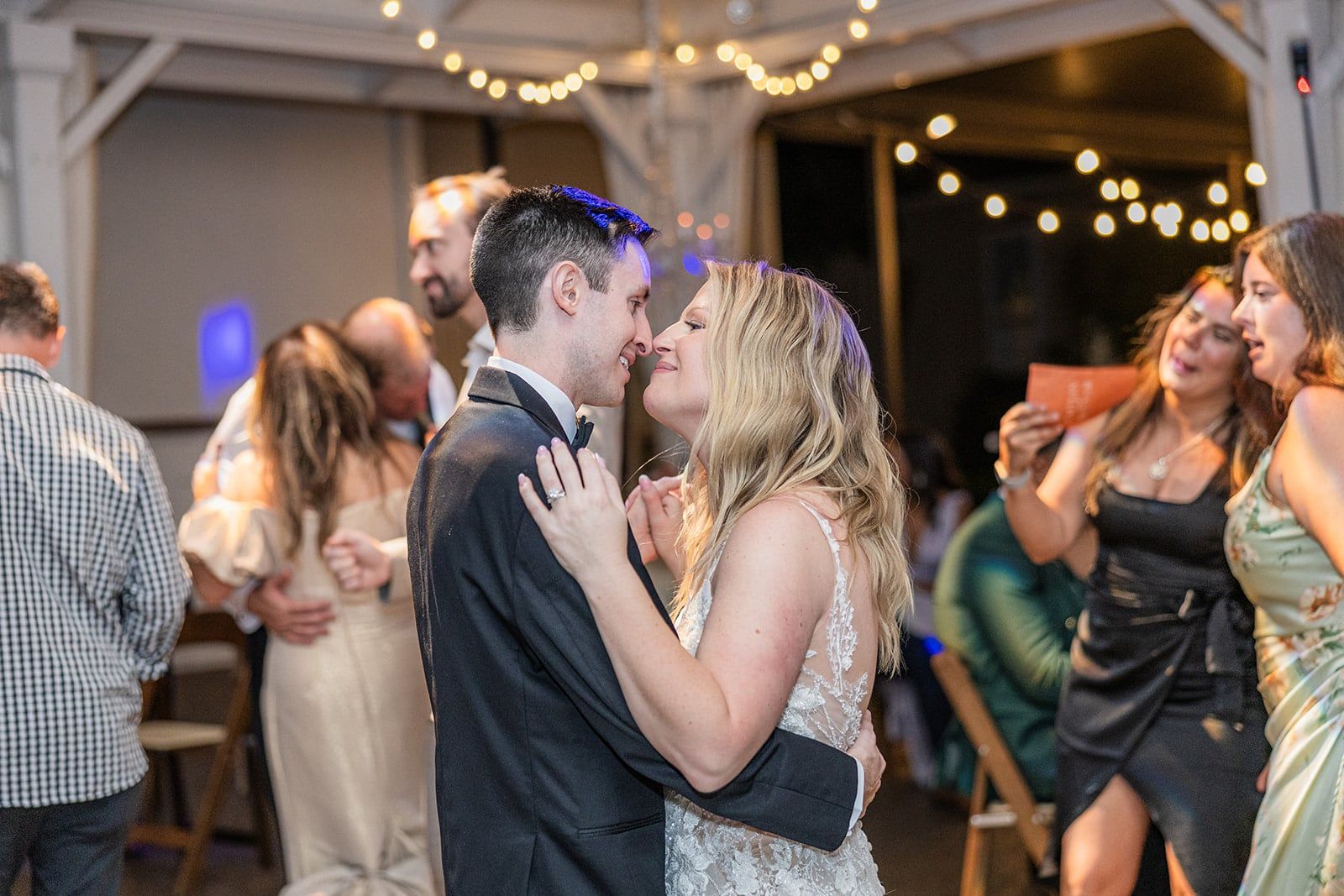 Caitlin and Gunnar hold each other on a packed dance floor as friends celebrate around them
