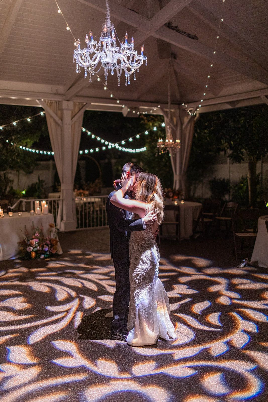 Caitlin and Gunnar's last dance under the chandelier, patterned light at their feet