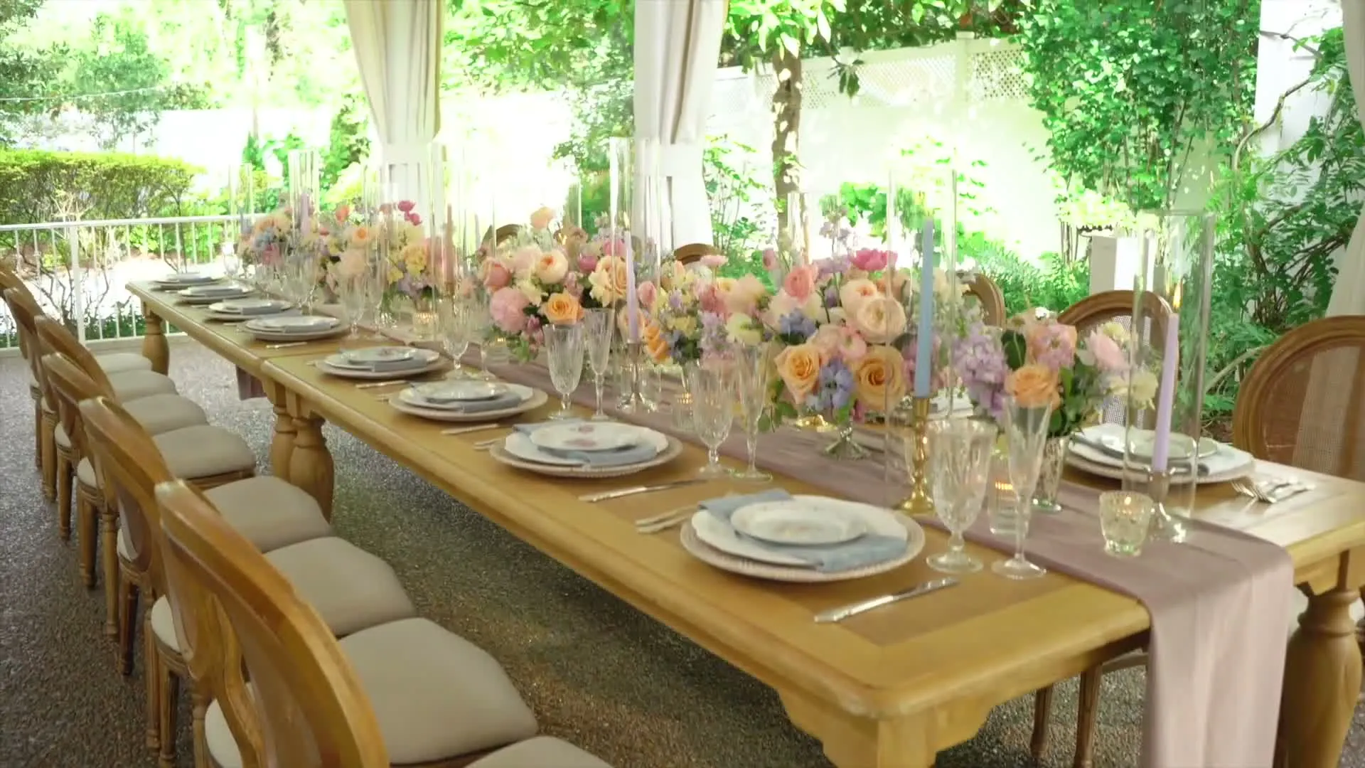 A long garden reception table set with pastel flowers, taper candles and crystal glasses under the tent at CJ's Off the Square