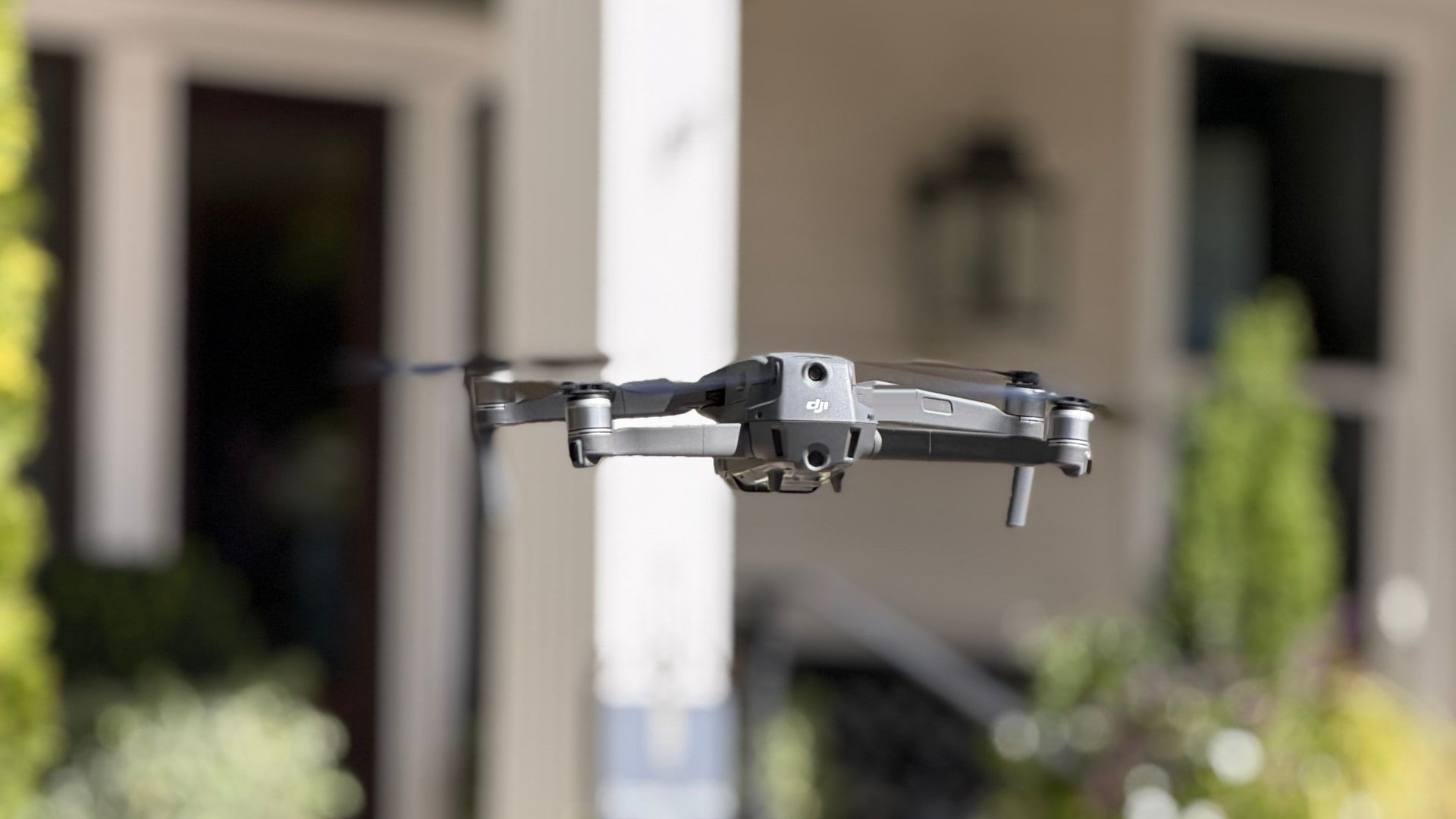 Our camera drone in flight at a wedding, the venue's porch, lanterns and white flowers soft in the background