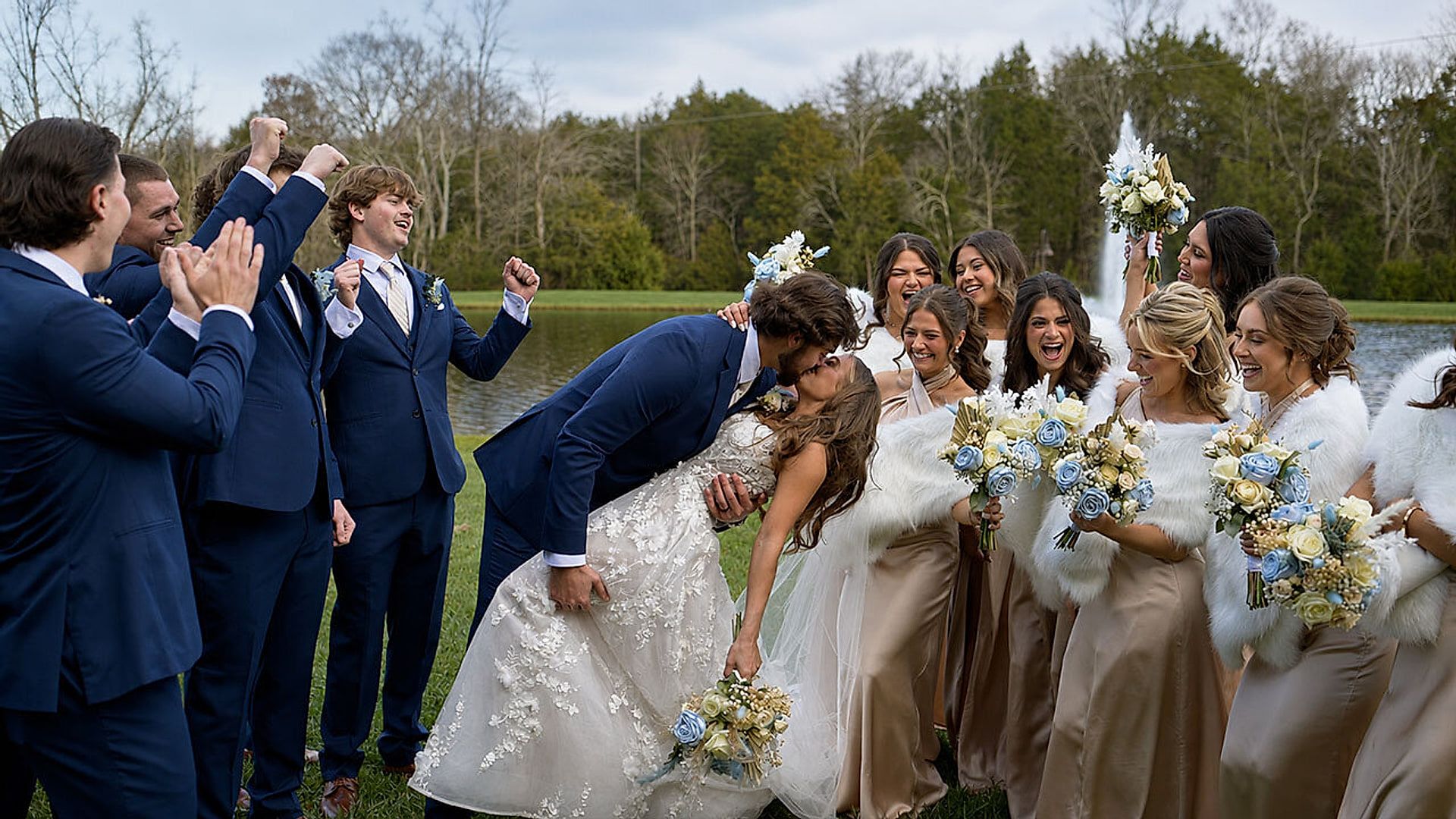 Sami and Blake's wedding party cheers as the couple kiss beside the lake at Sycamore Farms
