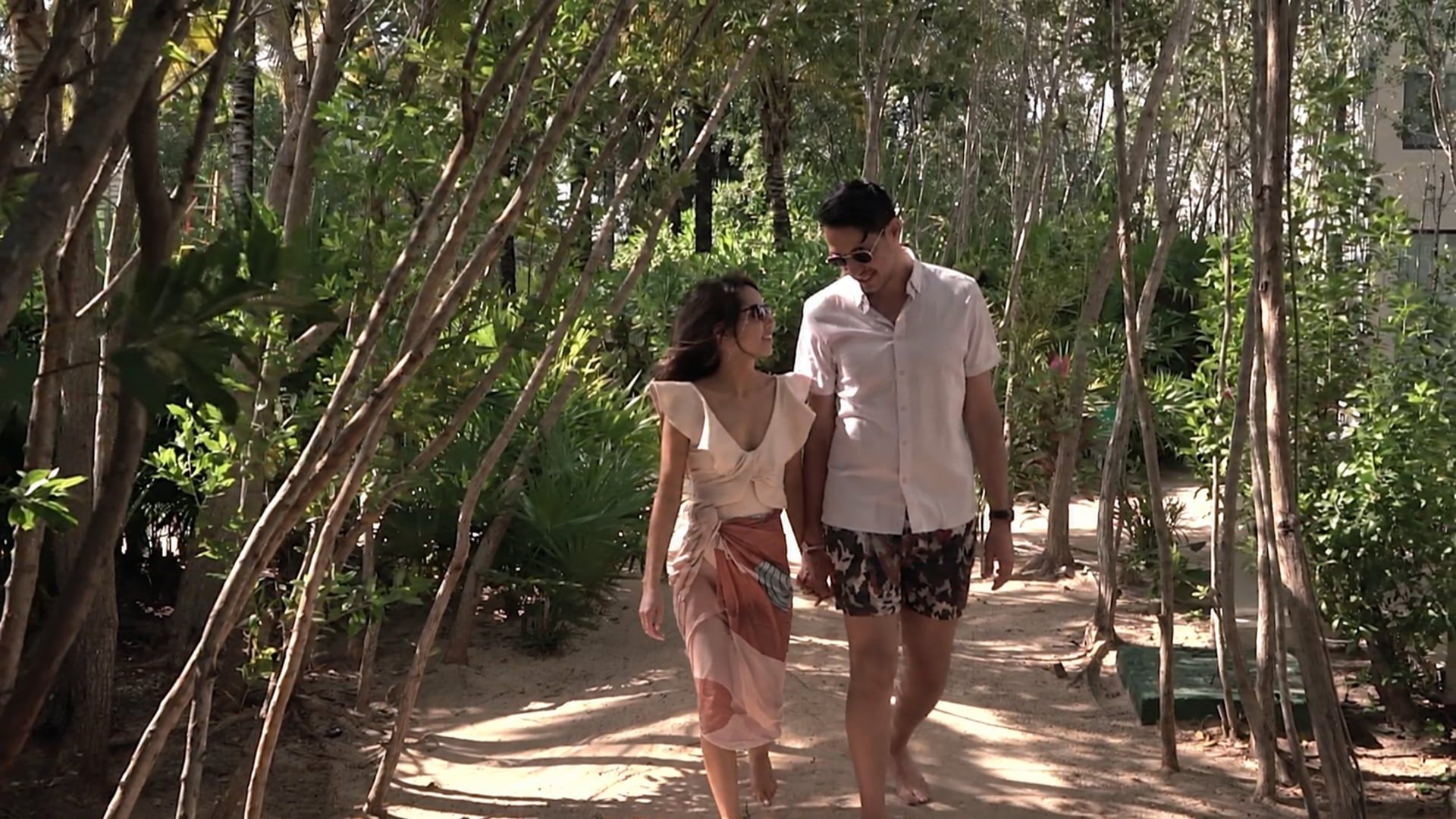 Tonya and Ori walk hand in hand down a sandy path through the trees on the Riviera Maya, Mexico