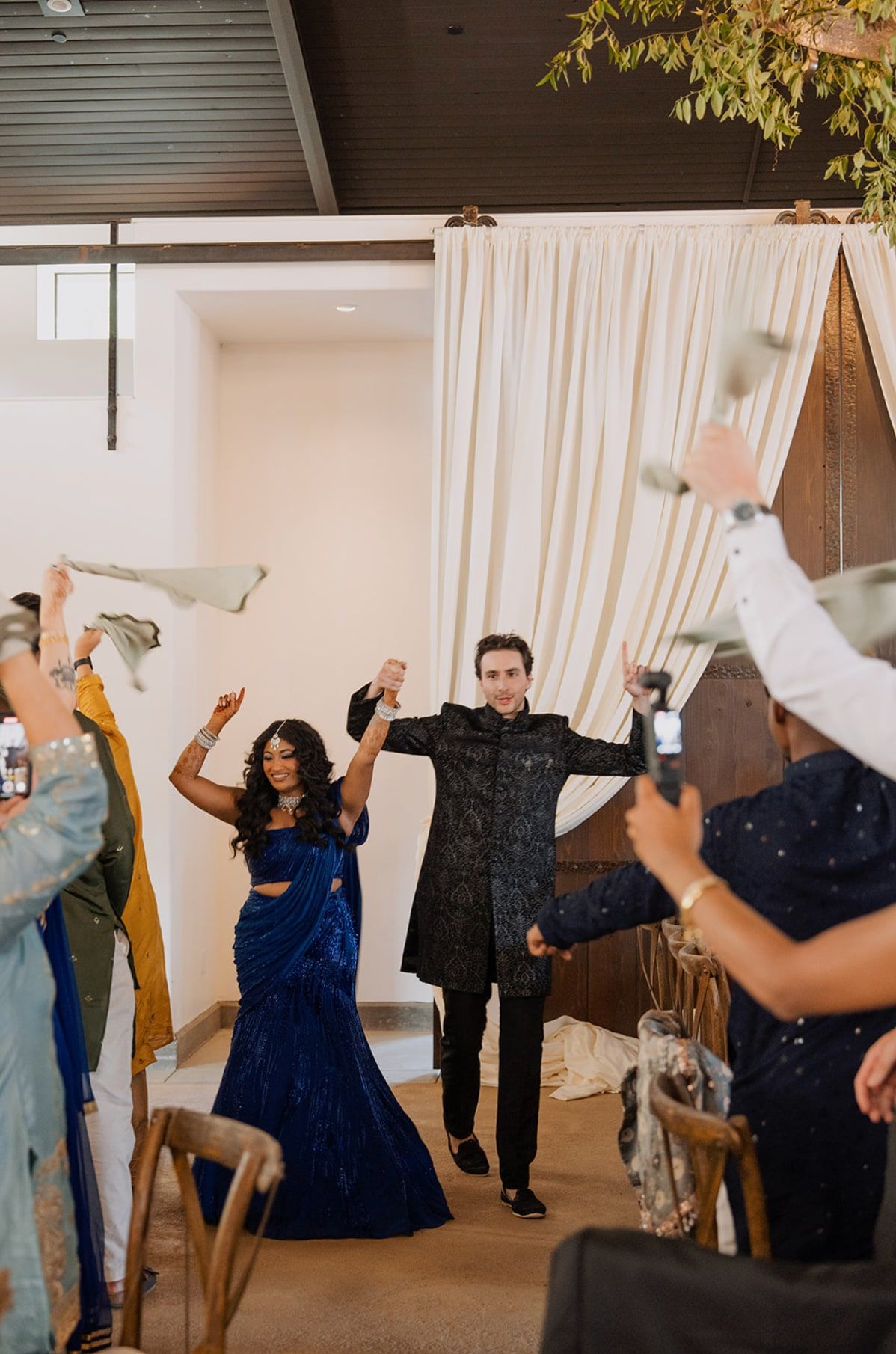 Couple dancing into their Indian and Irish fusion reception as guests wave napkins overhead