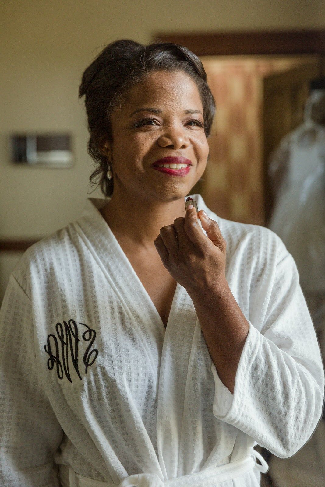 Smiling in a monogrammed white robe while getting ready on the wedding morning