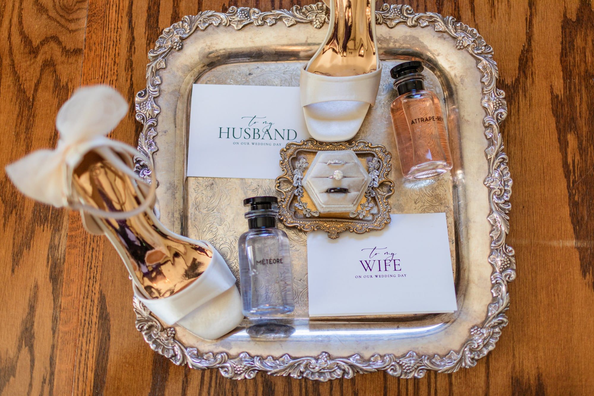 Wedding-morning details on a silver tray: shoes, perfume, a ring box and cards reading Husband and Wife