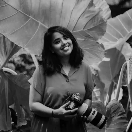 Tanya, our lead photographer for Indian weddings, smiling among giant green leaves