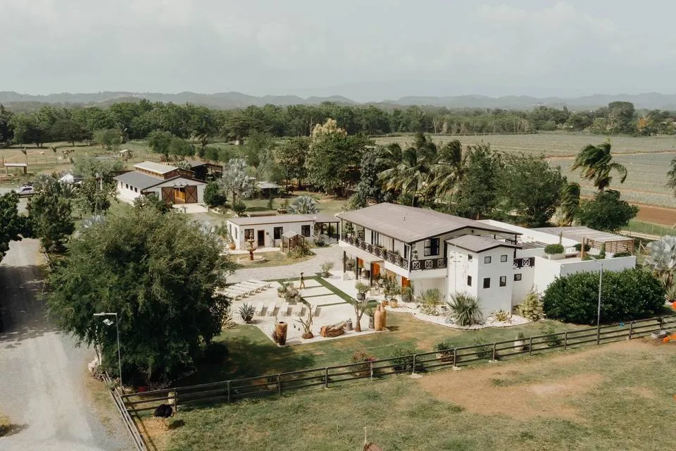 Aerial view of a white hacienda-style wedding venue in Puerto Rico, surrounded by palms and green fields