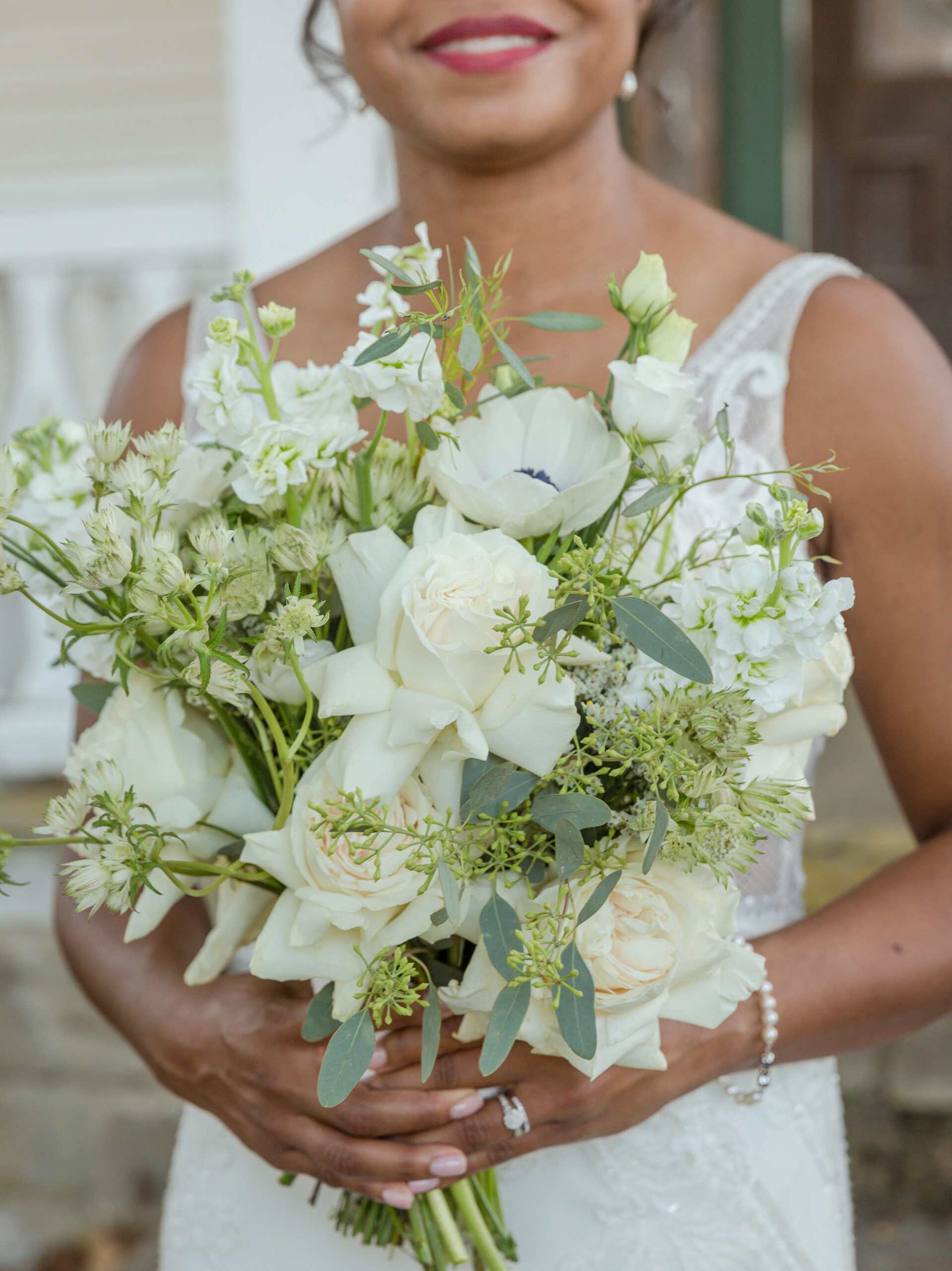 a bride holds her beautiful bouquet of white and green flowers