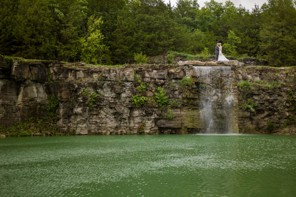 A bride and groom pose atop an epic waterfall at Nashville adjacent venue Graystone Quarry, a favorite venue of our wedding photo team.