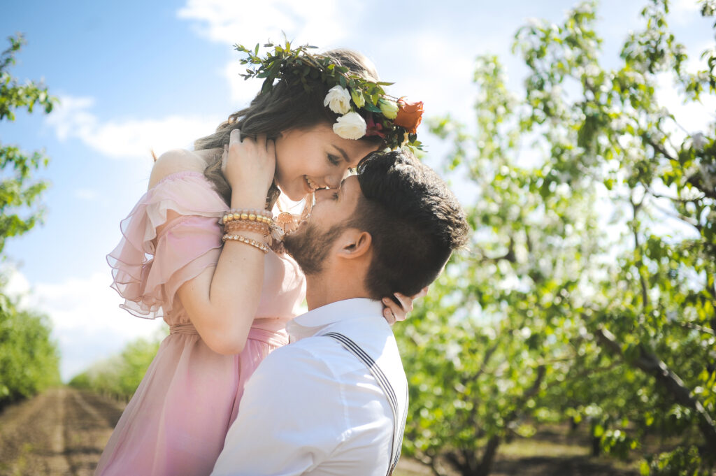 John lifts Susan as her pink wedding dress flows in the wind.  A flower crown in her hair.