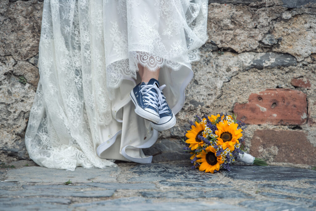 Bride Mary sits on a bride all with blue tennis shoes on in Nashville, her sunflower bouquet on the ground.