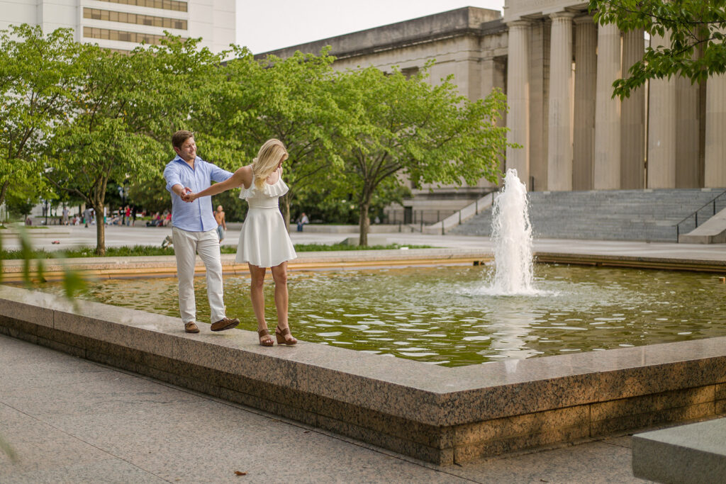 Fun bride in groom walk near a water fountain in Centennial Park in Nashville.  Best wedding photographers ever!