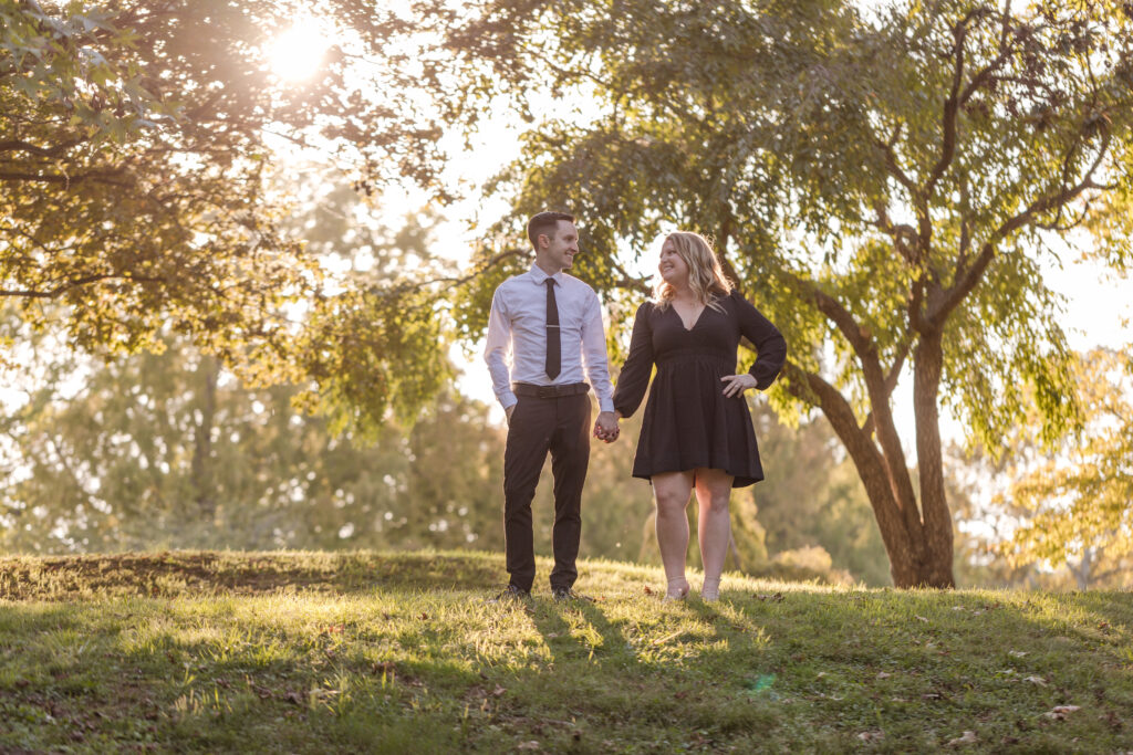 Groom and Bride pose under sun-lit trees during their engagement photo shoot in Nashville, Tennessee.