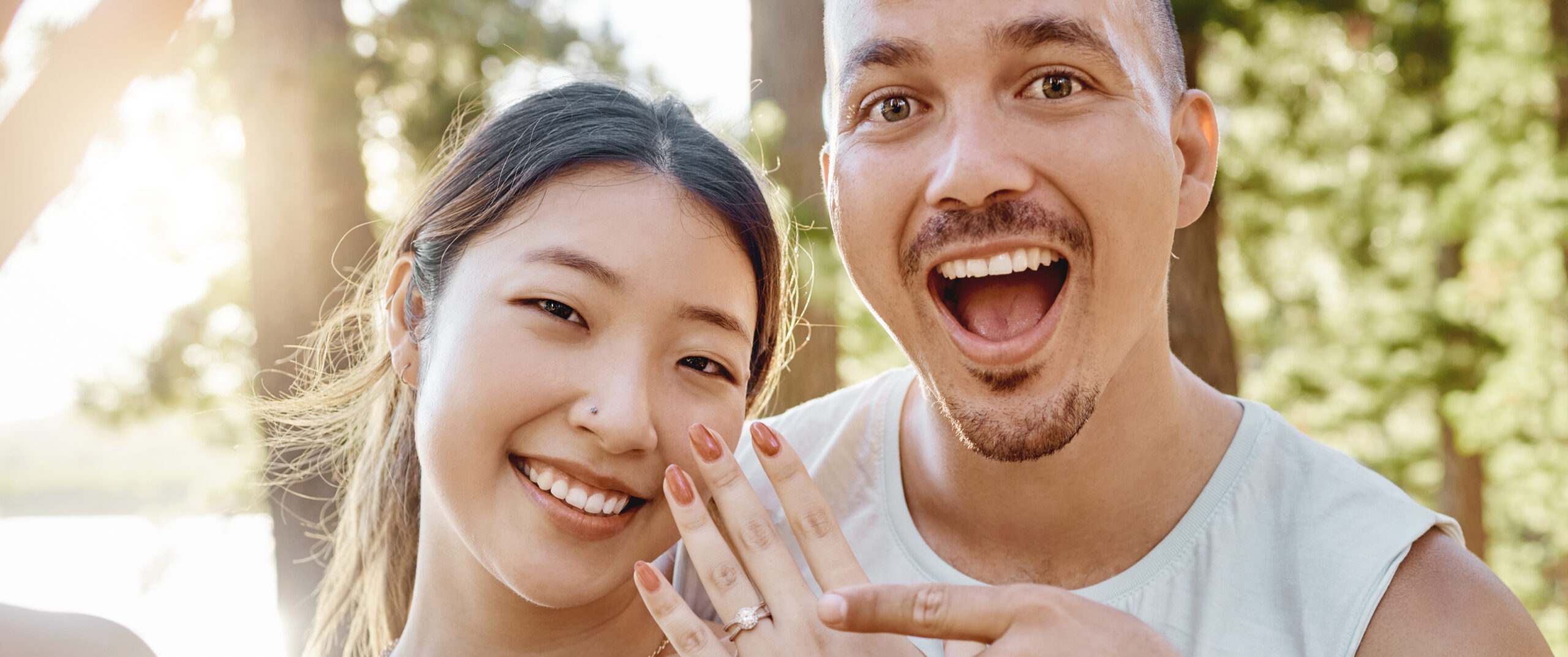 Couple, engagement and ring in selfie with smile, excited face and pointing for memory in forest.