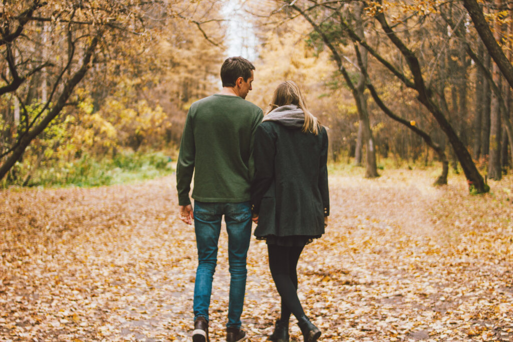 A young couple dressed in casual style sharing a romantic moment walking though a park and holding hands in Franklin, Tennessee.