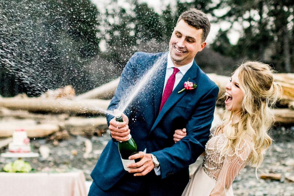 Bride Danielle and groom Brandon celebrate their marriage by popping a bottle of champagne at their destination wedding in the Pacific Northwest.