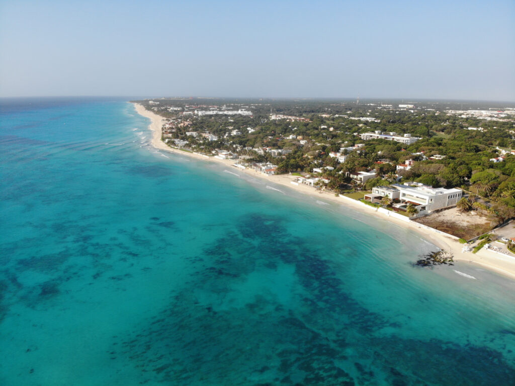 Aerial drone view of a tropical Mexico beach with clear blue water and white sand, perfect for destination wedding videography.