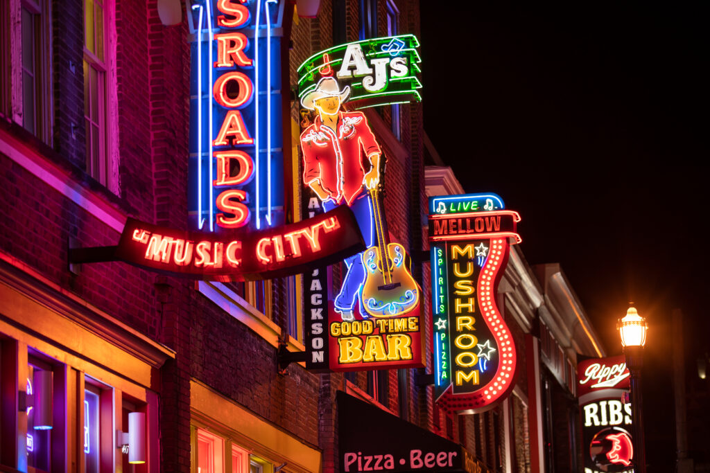 Vibrant neon signs of bars, restaurants, and honky-tonks on Broadway in downtown Nashville, a must-visit nightlife spot for bachelorette parties and weekend getaways.