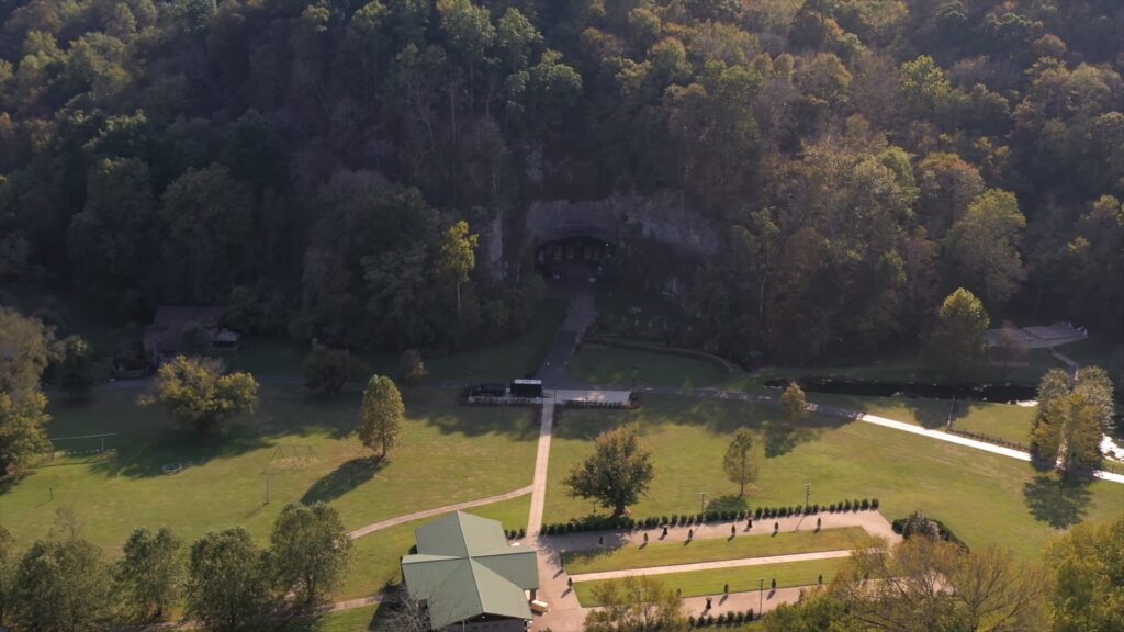 Aerial view of Ruskin Cave wedding venue in Dickson, TN, surrounded by forest and bathed in golden afternoon light. Captured by With This Ring, Nashville wedding videographers specializing in cinematic drone footage and outdoor wedding films.