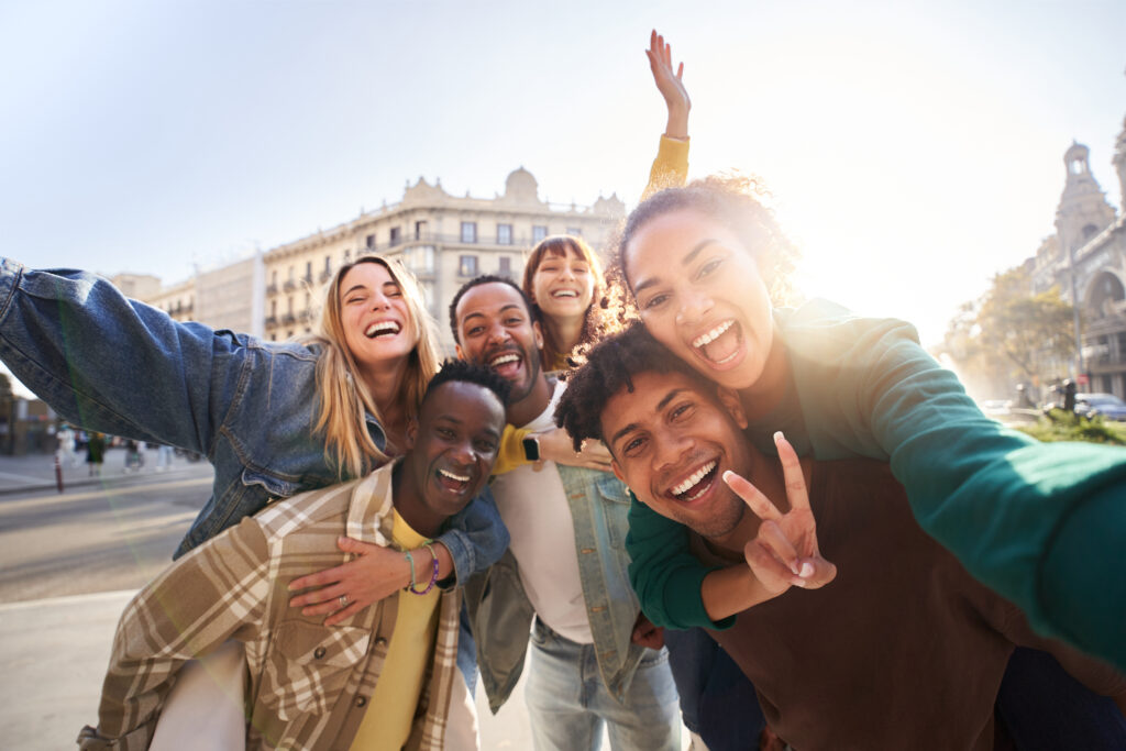Group of diverse Gen Z friends laughing and taking a selfie during a European vacation, symbolizing the personalized, joyful, and travel-focused spirit of modern Gen Z weddings.